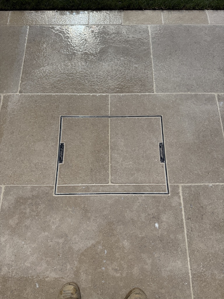 Close-up of a recessed access cover fitted neatly into Egyptian limestone paving