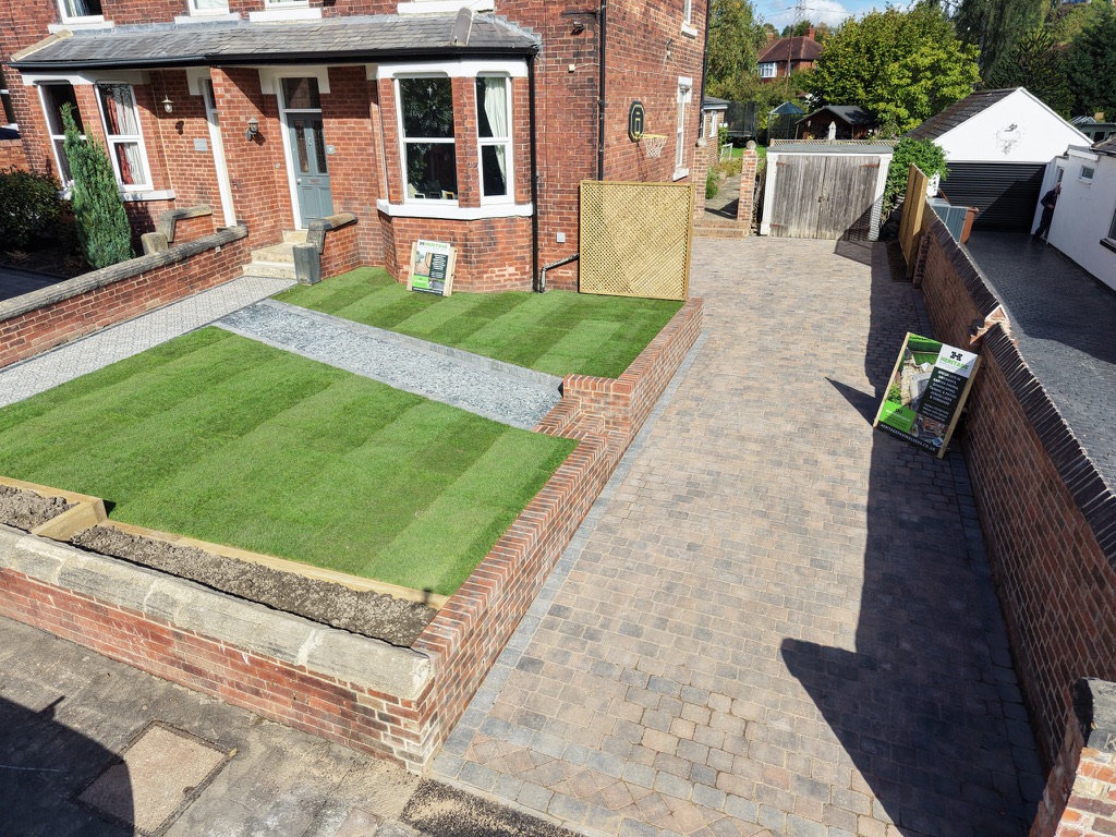 Completed block paved driveway alongside a striped lawn, boundary wall and timber gate by Heritage Paving