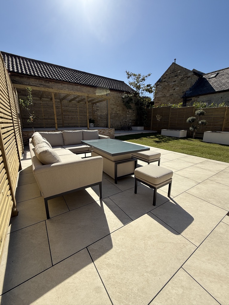 Large-format porcelain patio and outdoor seating beside a timber pergola in Linton