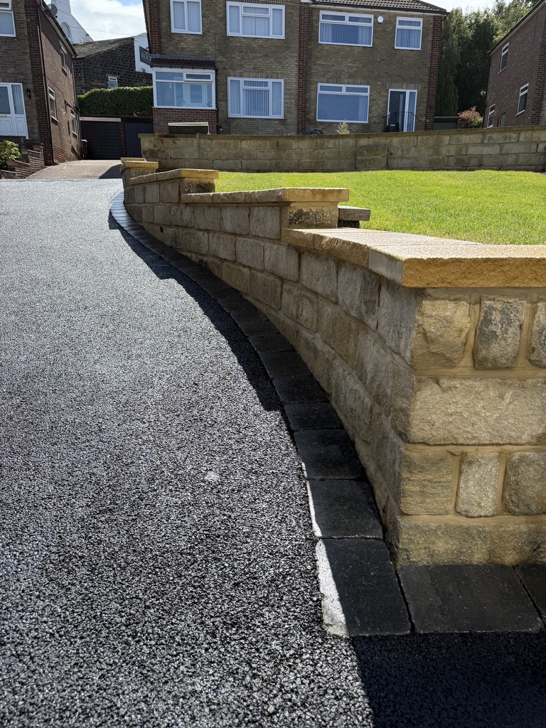 Tarmac driveway alongside a curved stone boundary wall
