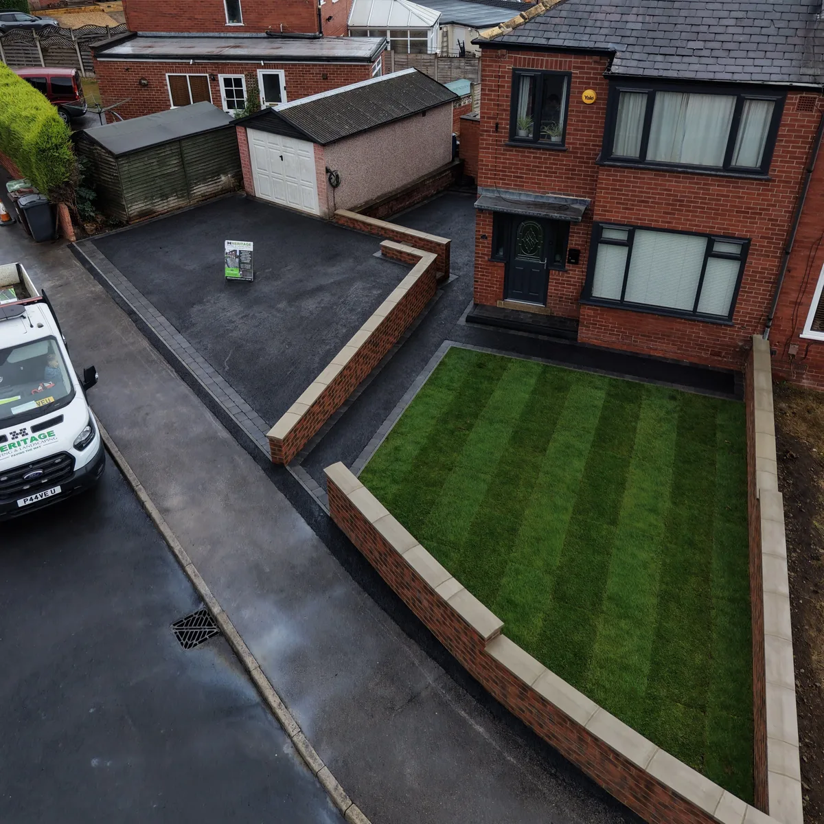 Aerial view of a finished Bramley tarmac driveway with brick walls, lawn and the Heritage van