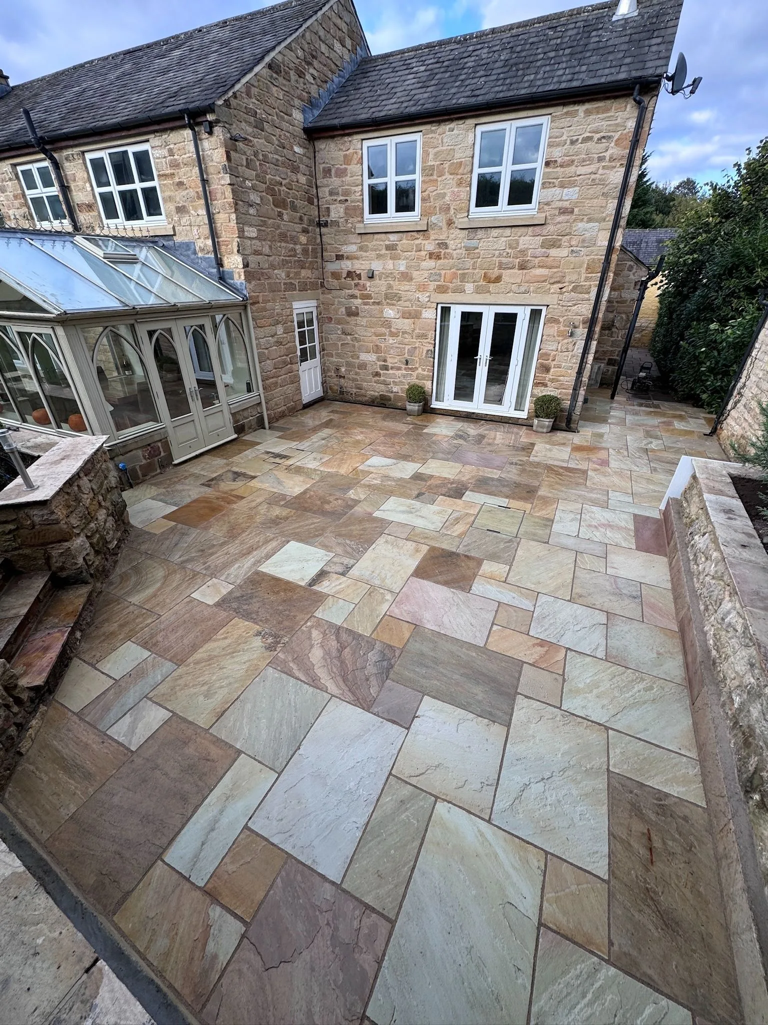 Fossil Mint Indian sandstone terrace laid beside a stone house in Linton
